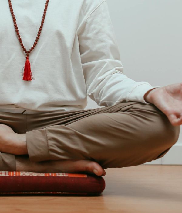 A person sitting calmly with hands in a mudra gesture.